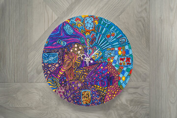 Step-by-step instructions for DIY round wall clock on canvas in technique of zentangle drawing pattern: step 6- colored painted,varnished product with clock hands on gray wooden background.Copy space.