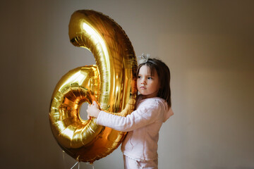 Fototapeta na wymiar Emotional girl child with balloon number 6, children's birthday, sixth birthday girl. Sad Child with Balloon
