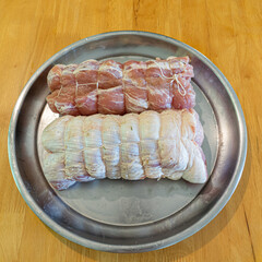 Trussed pork loin with rosemary on a steel tray