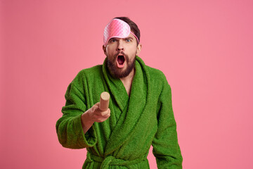 Portrait of a man in a pink sleep mask and a wooden rolling pin emotions green robe irritability model