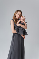 Portrait of happy mother with her baby isolated on grey.family, child and parenthood concept - happy smiling young mother with little baby at studio.Portrait of young mother and her adorable baby.