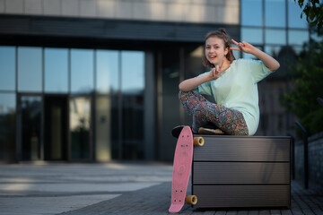 Fototapeta premium stylish teenager sit and rest with penny board after skateboarding in street