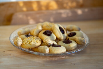 Light brown beige baked peanut cookies filled with dark chocolate, one by one on the plate, tasty Christmas sweets ready to eat