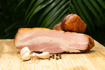Smoked bacon. Cold cuts on a wooden board with garlic, cumin and black pepper