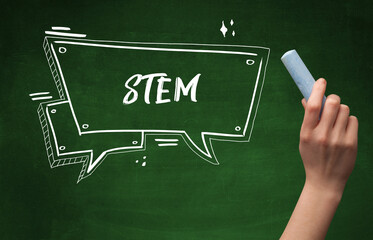 Hand drawing STEM abbreviation with white chalk on blackboard