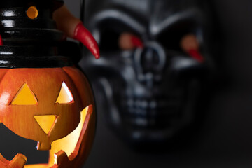 Halloween background. Glowing pumpkin and black skull on a dark background. Human fingers with long red claws