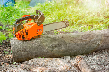 Gasoline powered professional chainsaw on pile of cut wood and timber, lumberjack and sawdust. Selected focus