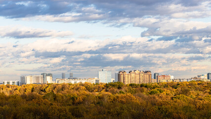 Fototapeta na wymiar panoramic view of urban park and residential district on horizon lit by autumn sunset sun in Moscow city