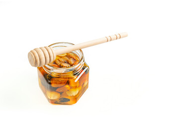 Jar of honey with nuts and honey spoon in a wooden box with sawdust, top view