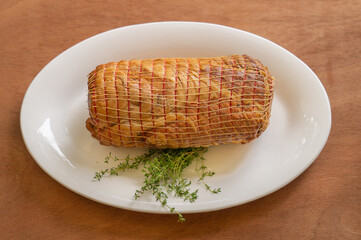 Smoked pork ham with thyme. Whole piece on a white plate