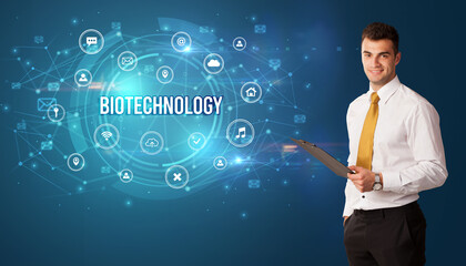 Businessman thinking in front of technology related icons and BIOTECHNOLOGY inscription, modern technology concept