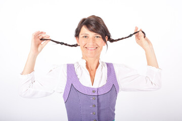young brunette woman wearing a bavarian dirndl and playing with her pigtails