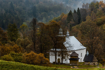 Lopienka Orthodox Church in Bieszczady Mountains. Fall Season in Mountains. Fog and Mist over COlorful Trees