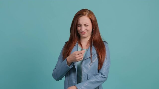 Close up of an young woman that is showing disgust, pinching her nose to avoid bad smell. Negative emotions, nasty feelings.
