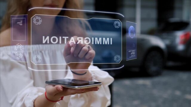 Unrecognizable blonde woman standing on the street interacts HUD hologram with text Immigration. Girl in white clothes uses technology of the future mobile screen