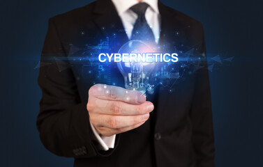 Businessman holding light bulb with CYBERNETICS inscription, innovative technology concept