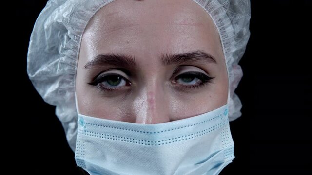 Tired nurse looking at camera on black background