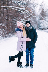 Fototapeta na wymiar Smiling beautiful couple walking in winter park and looking at camera