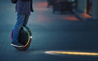 Riding fast on electric unicycle on city street at night with diode headlights. Night riding, man on electric mono-wheel riding fast (EUC). Mobile portable individual transportation vehicle. © Tricky Shark