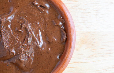 Top close view of a bowl of chocolate almond hazelnut butter on a table.