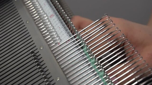 Female hands making textile on weaving machine at factory. Knitting machine Close up of weaving fabric on loom machine. Manufacturing knitted fabric on manual knitting equipment. Textile industry