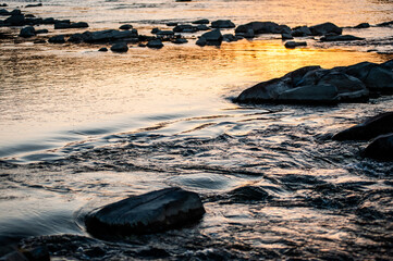 Sunset and its reflection in the water with stones