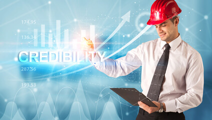 Young businessman with helmet drawing CREDIBILITY inscription, modern business technology concept