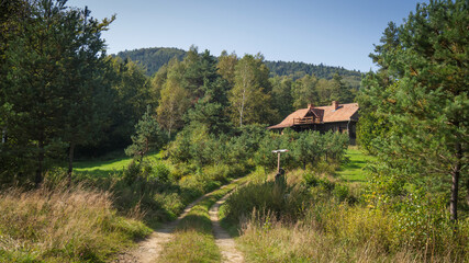 Wooden cottage house in forested mountains and hills area. Beskid Niski, Poland, Europe.