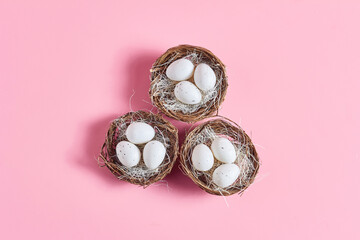 minimalistic Easter composition. decorative nests with white eggs on a pink background. flat lay, top view