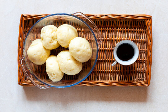 Steamed yeast dumplings and chocolate sauce for pouring on wicker tray. Homemade simple dessert flat lay. Traditional Polish cuisine.