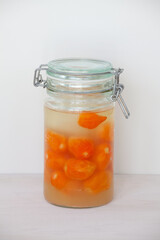 Habanero peppers in glass jar during fermentation process. Orange hot chili peppers fermenting.