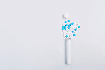 creative medical concept. simple composition of an open container and blue pills on a white background. flat lay, space for text
