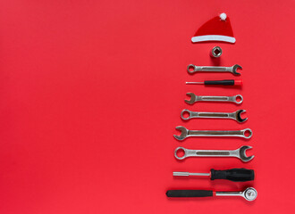 Christmas tree made of construction tools with a New Year's red hat on a red background. New Year...