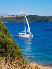 White catamaran yacht sailing boat alone on blue sea and cloudless sky