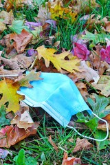 View of a used surgical mask discarded in foliage outdoors