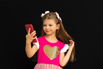 A little girl takes a picture of herself on her phone.