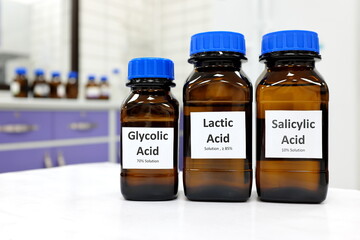 Selective focus of salicylic, lactic and glycolic acid liquid solution in dark brown glass bottle in a white chemistry laboratory background. Chemical peel for skincare research cosmetics industry.