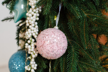 Christmas tree background. New Year composition with spruce, balls and lights. beautiful decorative pink ball on the spruce. Traditional Christmas toys with beautiful ornament