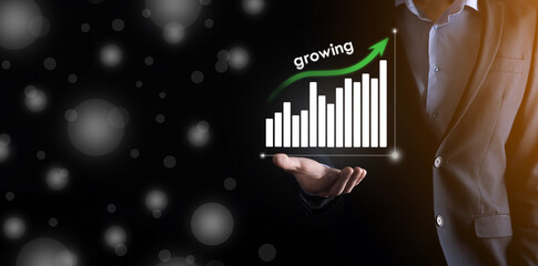 Business man holding holographic graphs and stock market statistics gain profits. Concept of growth planning and business strategy. Display of good economy form digital screen.