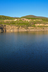 Stone rocks near water, on the background of lake, river, sea, ocean. Blue clear water. Artificial reservoirs