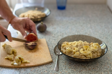 Fototapeta na wymiar Bowl of oat flakes on kitchen table. Male hand cutting figs for oatmeal porrige.