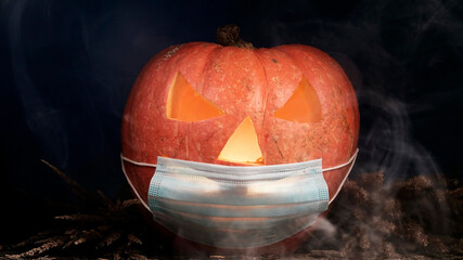 Halloween carved pumpkin glowing with protective medical face mask, coronavirus and quarantine concept, covid-19 halloween costume. eyes change brightness. White smoke. head turns clockwise