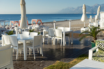 Famous Konyaaltı beach and the Mediterranean sea, white chairs and tables. Close-up photo, Antalya Turkey