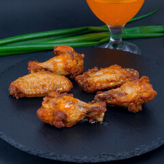 Fried chicken drumsticks on the black stone tray with some green onion