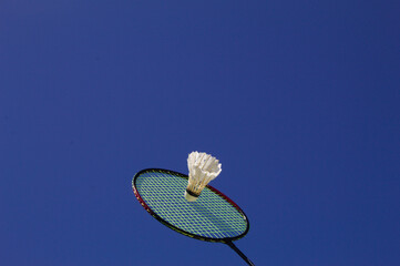 Raquete de badminton com peteca e fundo do céu azul
