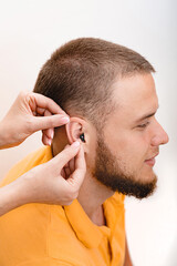 Man patient with Intra-ear hearing aid, close-up inside the male ear. Hearing solution, audiologist inserting hearing aid to patient