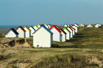 The tiny white beach cottages with colorful roofs at a beach by Gouville-sur-Mer in France in Normandy. The attraction for the tourists. 
