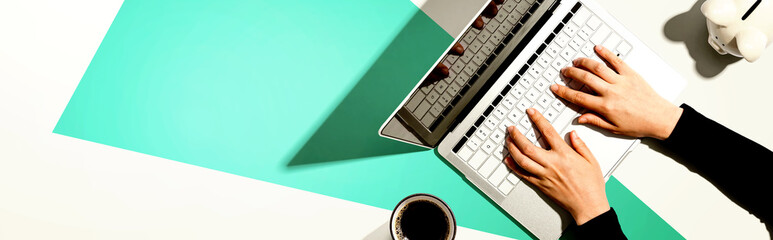 Person using a laptop computer with a piggy bank - flat lay