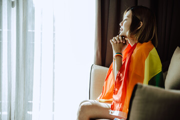 Asian girl and rainbow flag, Young lesbian sit alone in living room.