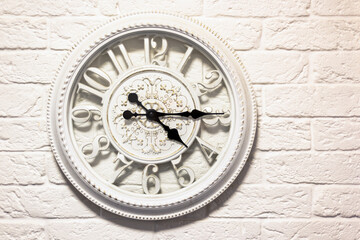 Fototapeta na wymiar white, vintage wall clock on a white brick wall.
